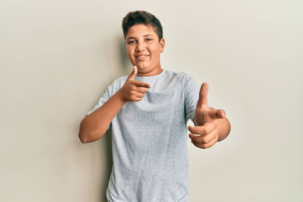 Adolescente hispano con camiseta gris casual señalando con los dedos a la cámara con cara alegre y divertida. buena energía y vibraciones.  - Foto, Imagen