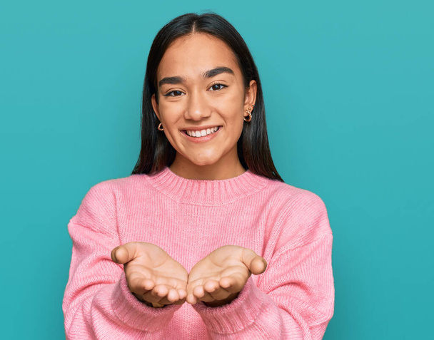 Young asian woman wearing casual winter sweater smiling with hands palms together receiving or giving gesture. hold and protection  - Photo, Image