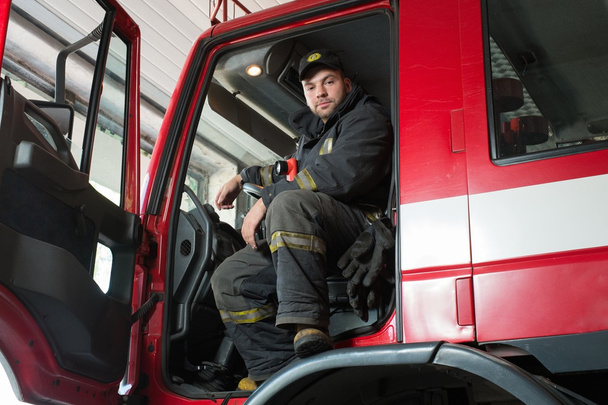 Fireman behind steering wheel of a firefighting truck  - Fotografie, Obrázek