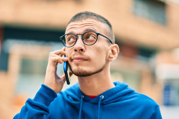 Sakin yüzlü genç İspanyol adam şehirde akıllı telefondan konuşuyor.. - Fotoğraf, Görsel
