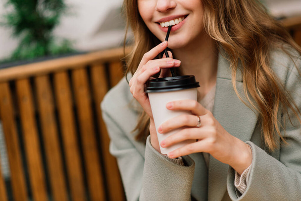 Hermosa mujer caucásica bebiendo café en la cafetería, sonriendo, hablando por teléfono - Foto, Imagen