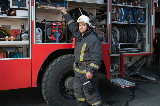 Fireman taking equipment from firefighting truck  - Fotoğraf, Görsel
