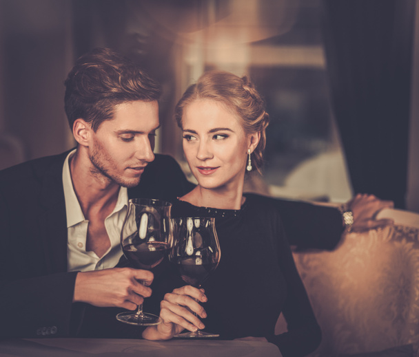 Hermosa pareja joven con copas de vino en el interior de lujo
 - Foto, Imagen