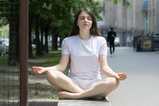 Женщина медитирует на улице в городе. Медитация и йога - Фото, изображение