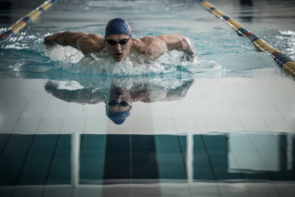 Hombre joven en gorra de natación y gafas nadan usando la técnica de la braza
  - Foto, imagen