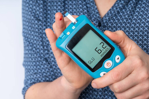 Kobieta z cukrzycą sprawdza stężenie cukru we krwi za pomocą glukometru - Zdjęcie, obraz