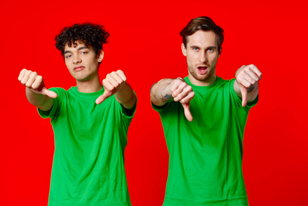 Happy Friends in Green T-shirts Show Thumbs Down Emotions - Photo, Image