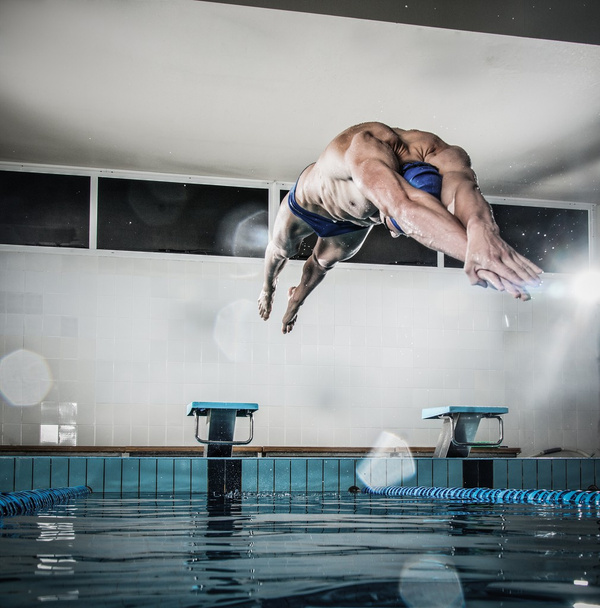 Joven nadador muscular saltando desde el bloque de partida en una piscina
 - Foto, imagen