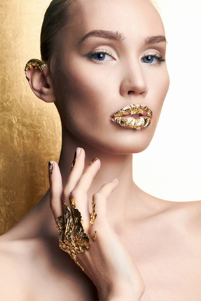 Beautiful model girl with golden makeup. beauty fashion portrait. young woman with gold paint on lips - Foto, Bild
