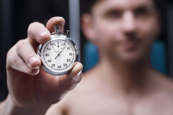 Mechanical stopwatch in a hand. Man athlete with a clock face. Fitness and sport concept - Foto, Imagen