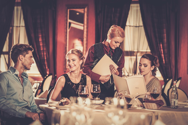 groep van jonge vrienden met menu's kiezen in een luxe restaurant - Foto, afbeelding