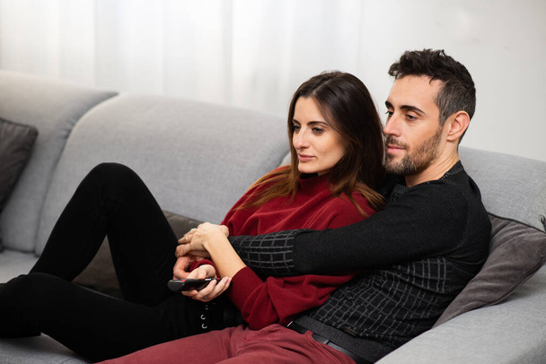 Couple watching a movie together on a couch - Фото, изображение