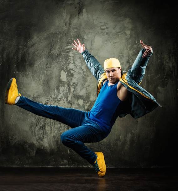 Mies tanssija lippis ja takki osoittaa break-tanssi liikkuu
 - Valokuva, kuva