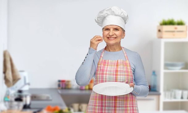 smiling senior woman or chef holding empty plate - Zdjęcie, obraz