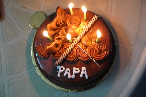 Gâteau d'anniversaire pour papa écrit "Joyeux anniversaire Papa" sur la table. Moment de paternité jour spécial. Célébration anniversaire de maman, papa ou maman et papa. Gâteau au chocolat anniversaire avec bougies allumées. JYD - Photo, image
