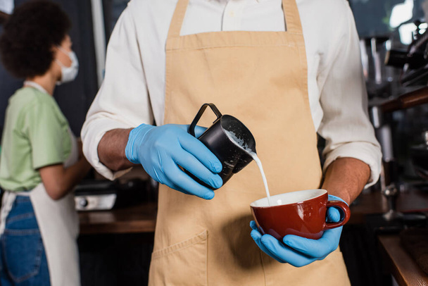 アフリカ系アメリカ人のバリスタ、ラテックス手袋でコーヒーを作るカフェでミルク  - 写真・画像