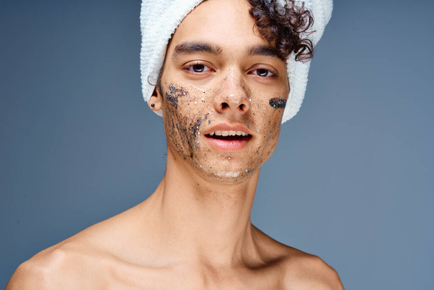 Chico alegre con una toalla en la cabeza cosméticos en la cara piel limpia - Foto, imagen
