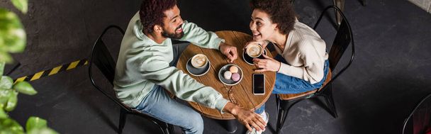 Overhead view of cheerful african american coupe with coffee dating in cafe, banner  - Фото, изображение