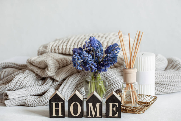 Spring home composition with flowers, aroma sticks, knitted element and decorative word home. - Photo, Image
