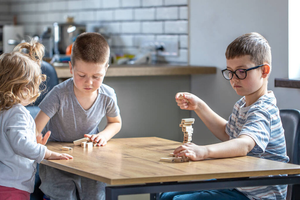 Małe dzieci grać w grę planszową z drewnianymi kostkami w domu w kuchni. - Zdjęcie, obraz