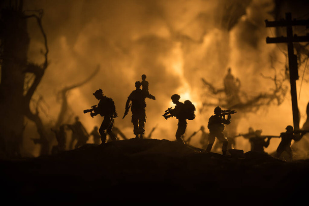 シルエットの兵士は肩に小さな男の子を火から運んでいる。救世主の概念を救う。戦争で破壊された都市から少年と一緒に出て行く男。選択的焦点 - 写真・画像