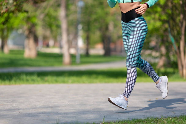 Женщина бегает рано утром в парке. Фото ног бегущей женщины крупным планом. Концепция здорового образа жизни и поддержание формы тела. - Фото, изображение