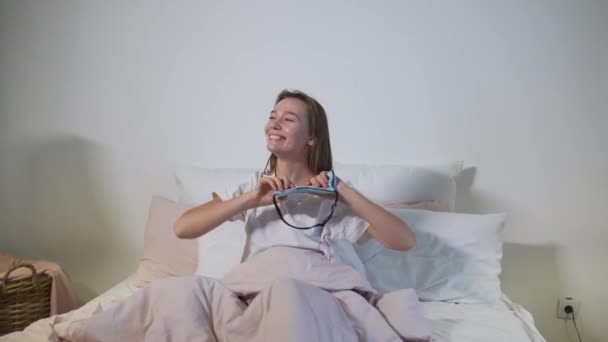 Счастливая сонная взрослая женщина просыпается в белой постели - Кадры, видео