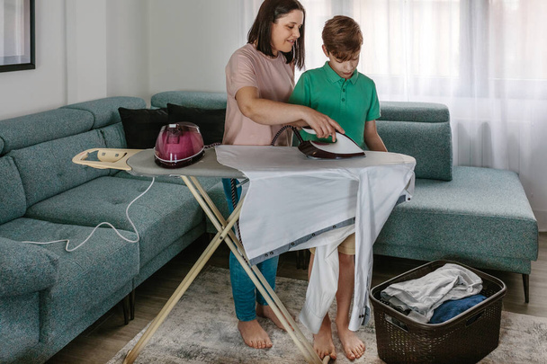 Mother teaching her teen son to iron - Photo, Image