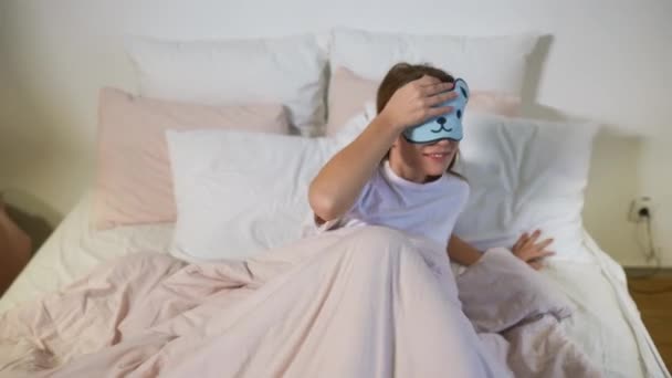 Ευτυχισμένη νυσταγμένη νεαρή ενήλικη γυναίκα που ξυπνάει ξαπλωμένη στο λευκό κρεβάτι - Πλάνα, βίντεο