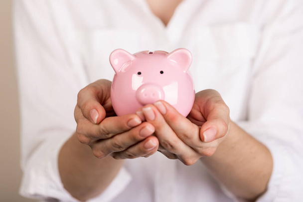 Piggy bank in hands on light background, space for text. Finance, saving money - 写真・画像