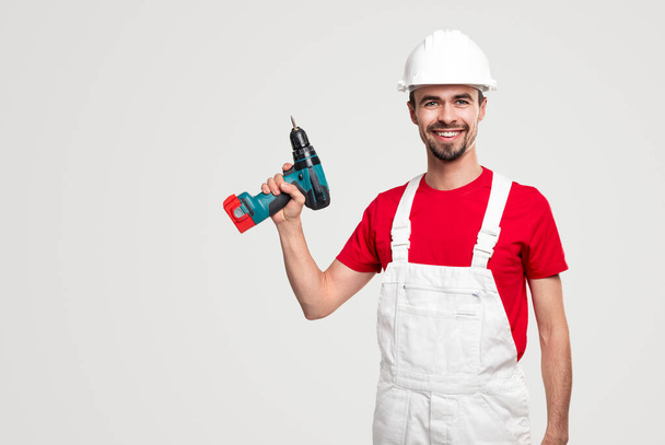 Cheerful handyman with electric screwdriver - 写真・画像
