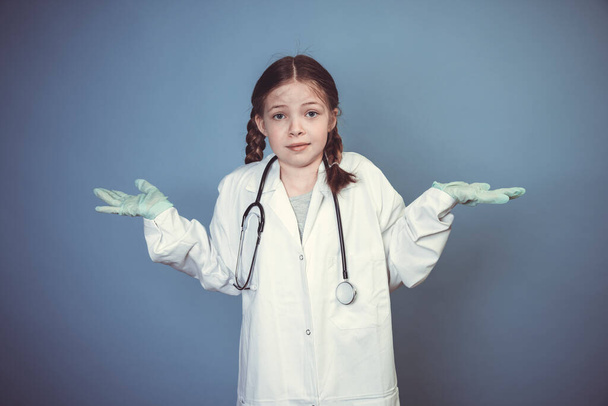 young girl dressed as doctor with green rubber gloves and stethoscope in front of blue background - Foto, immagini