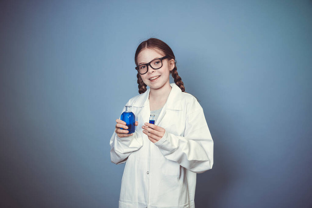 pretty girl with two braids is dressed as scientist and experimenting with blue liquids wearing black glasses - Fotoğraf, Görsel