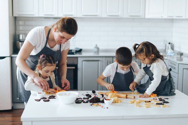 Mamá enseña a los niños a cocinar galletas de caramelo. Actividad de ocio con concepto infantil. - Foto, Imagen