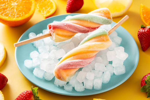 Sarı arkaplanda sarmal renkli buzlu şeker - Fotoğraf, Görsel