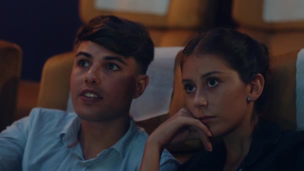 Привлекательная веселая молодая кавказская пара смеется во время просмотра фильма в кинотеатре. Концепция развлекательного образа жизни. - Кадры, видео