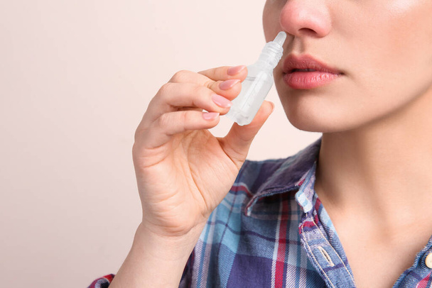 Woman using nasal spray on beige background, closeup. Space for text - Photo, Image