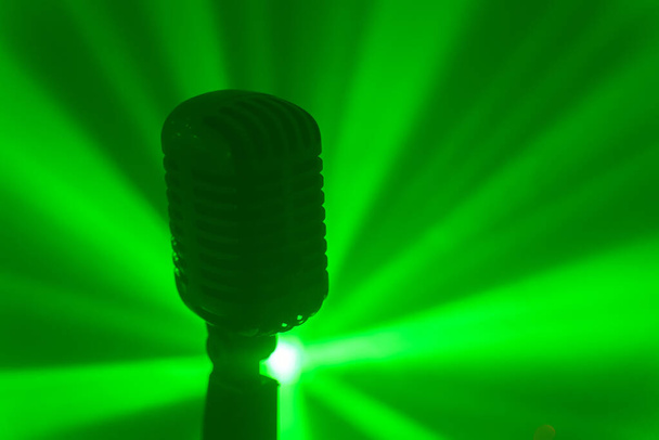 Zabytkowy mikrofon ze scenicznymi lampami disco. Koncepcja występu na żywo lub karaoke. - Zdjęcie, obraz