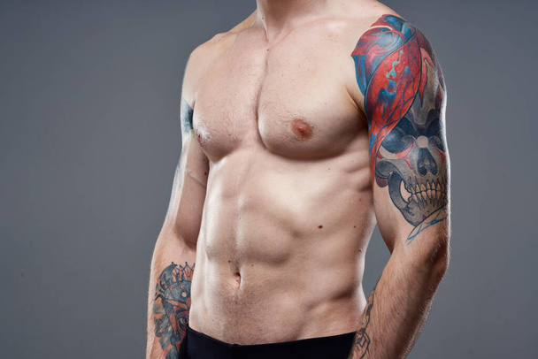 спортивний чоловік з зануреними татуюваннями абс на руках сірих м'язів тла
 - Фото, зображення