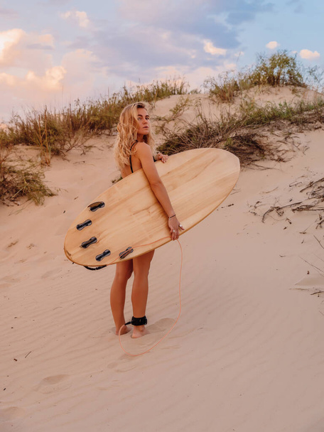 Chica surfista con tabla de surf en la playa y colores cálidos atardecer. Mujeres surfistas atractivas - Foto, imagen