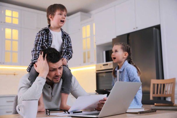 Overwhelmed man combining parenting and work at home - Foto, immagini