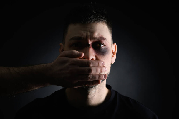 Person abusing adult man on dark background. Domestic violence - Foto, afbeelding