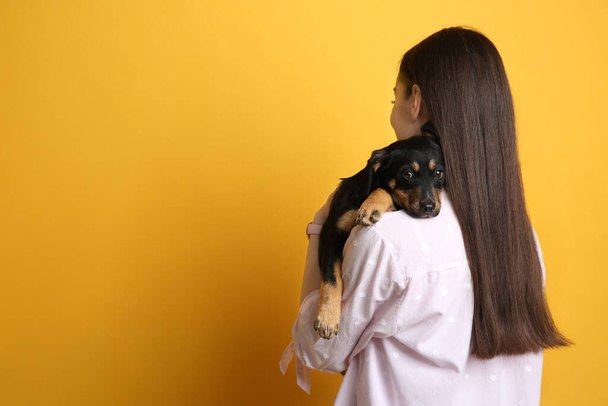 Woman with cute puppy on yellow background, space for text. Lovely pet - Foto, Bild