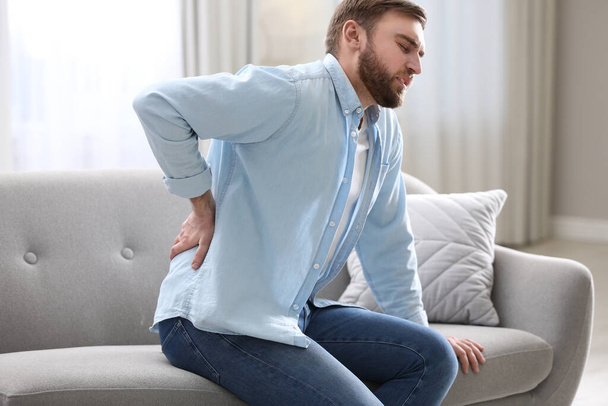 Man suffering from back pain at home. Bad posture problem - Foto, imagen