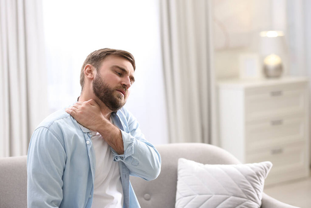 Man suffering from neck pain at home. Bad posture problem - Fotoğraf, Görsel