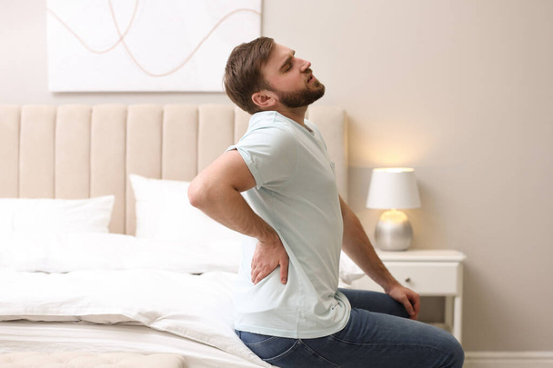Man suffering from back pain at home. Bad posture problem - Zdjęcie, obraz