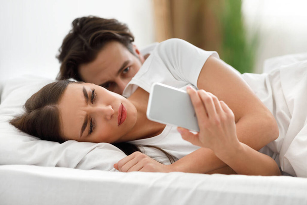 Féltékeny férj olvas hűtlen feleségek üzenetek, miközben ő SMS-ezik a házban - Fotó, kép