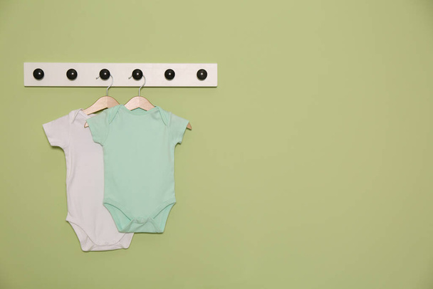 Baby onesies hanging on green wall, space for text. Interior design - Foto, Imagem