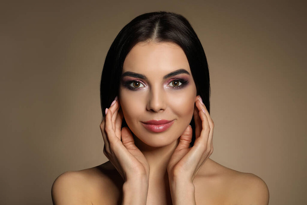 Beautiful young woman with evening makeup on brown background. Eye shadow product - Fotó, kép