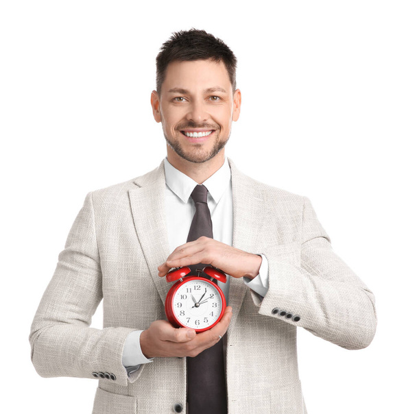 Happy businessman holding alarm clock on white background. Time management - Fotoğraf, Görsel